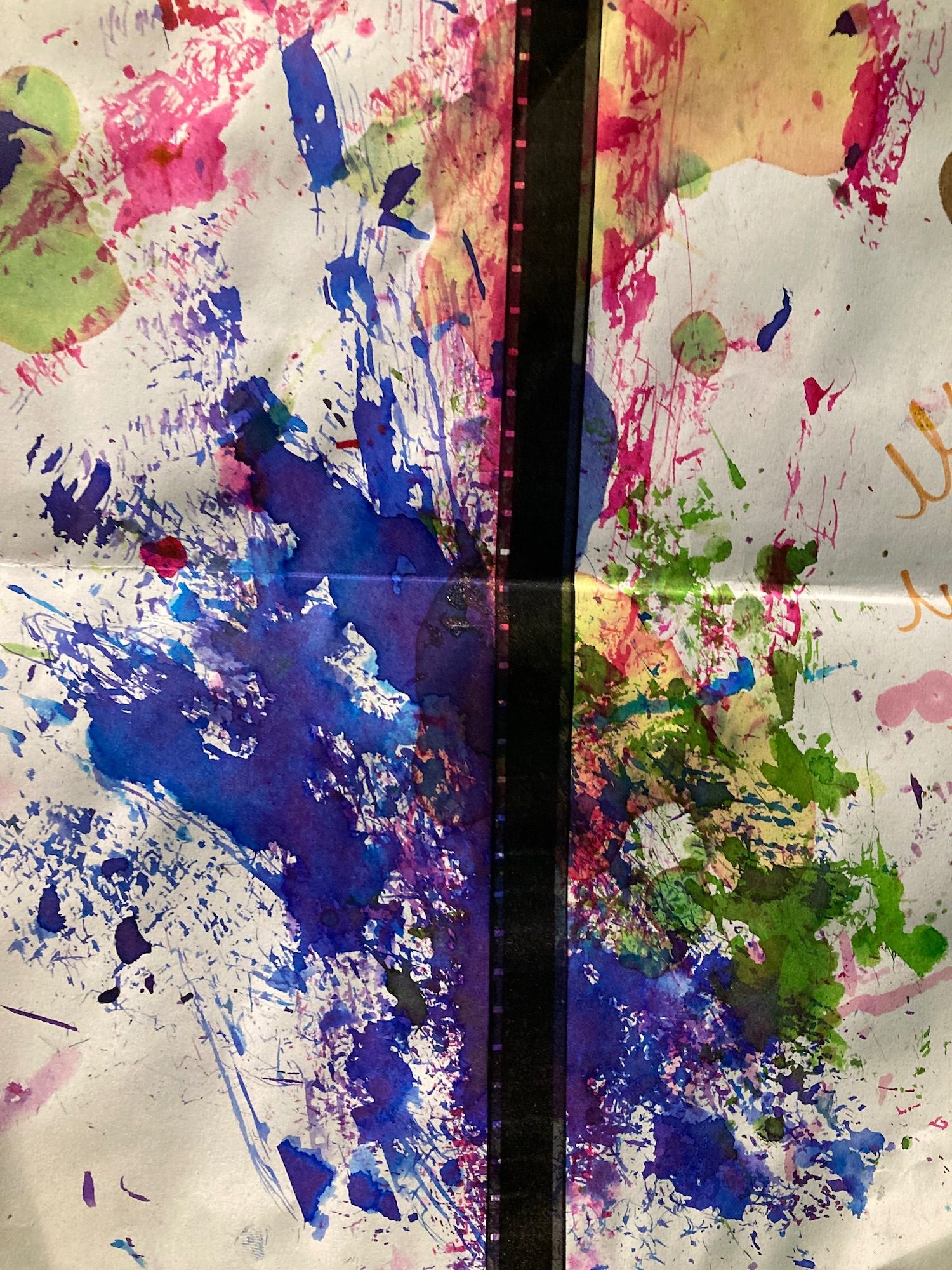An image of a white page, with a representation of a film strip down the middle, and multiple splashes of brightly coloured paint and nail varnish