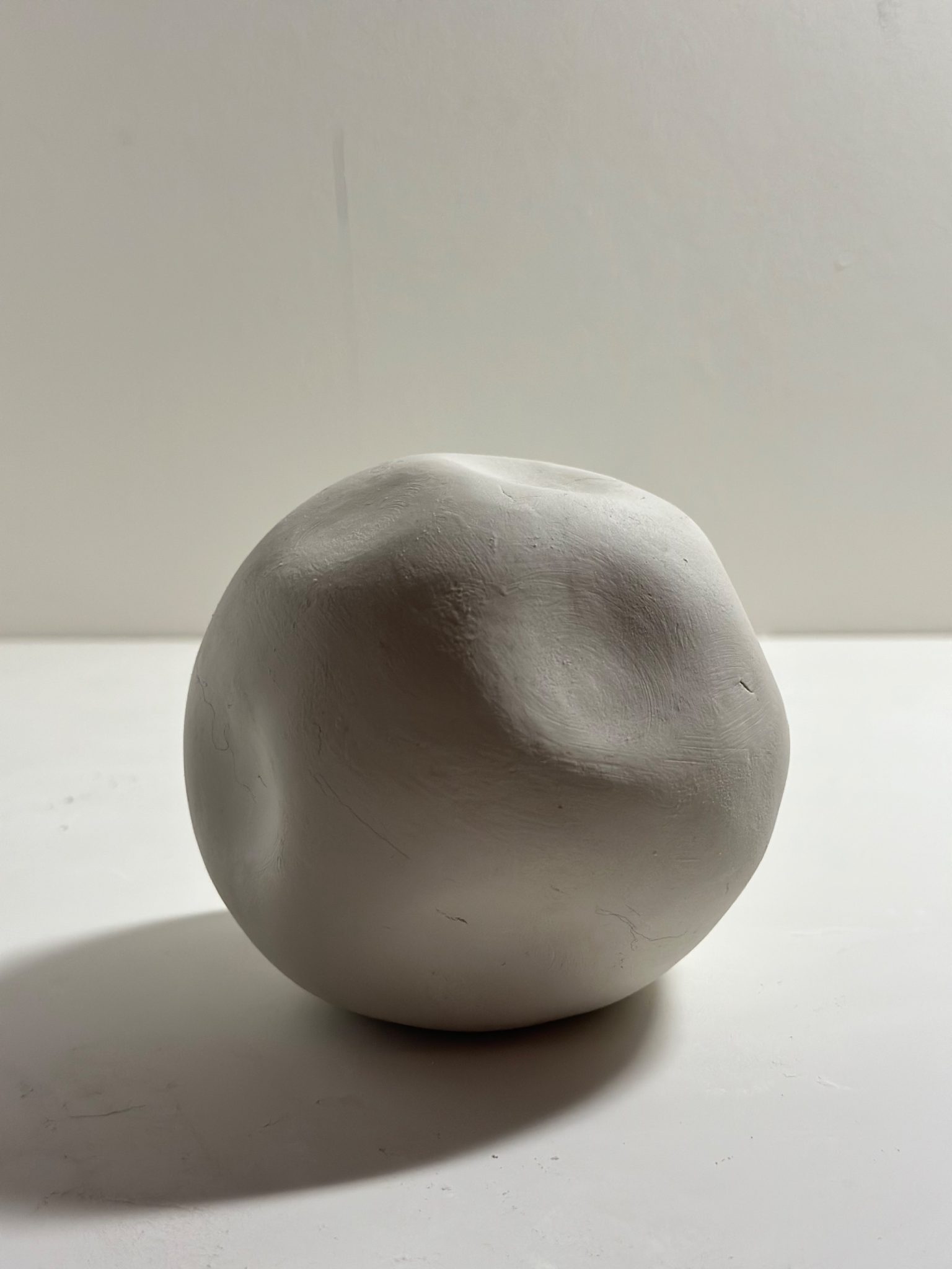 I divided a lump of clay into two equal parts and shaped each into a bowl form. I then joined them together to create a sphere. After rolling it in my hands for a while to refine the shape, I pressed my finger into the surface to make dents. However, due to the resistance of the air trapped inside, it did not indent as deeply as I expected.