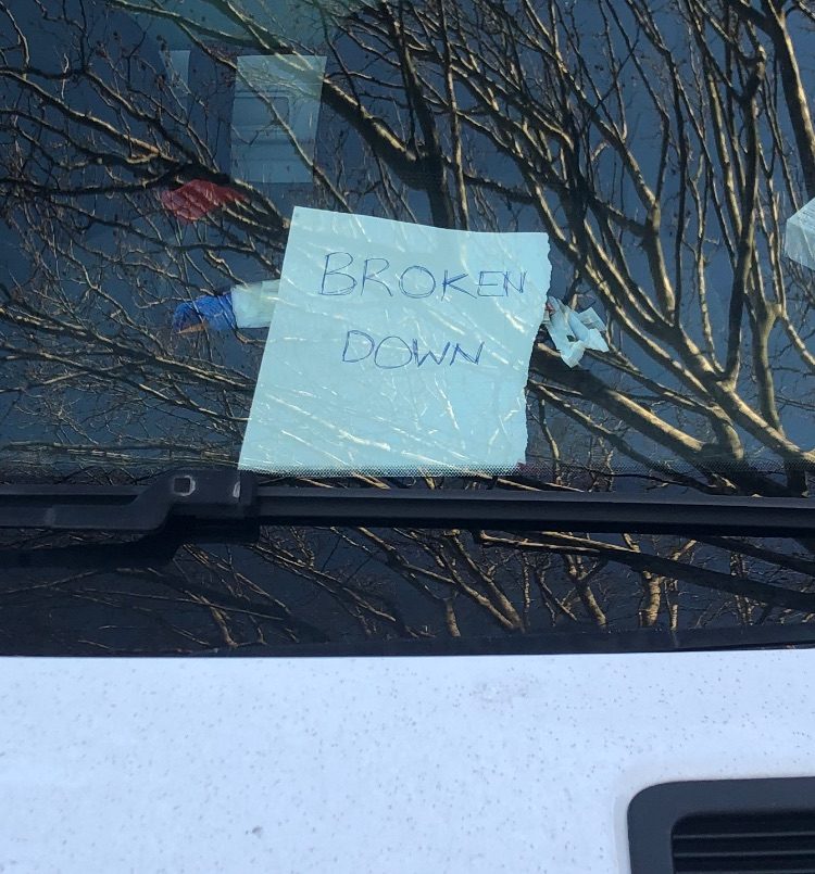 “BROKEN DOWN” written shonkily on a piece of white paper and put on the dashboard of a large work van