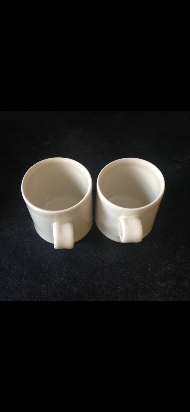 A pair of thrown white porcelain mugs
