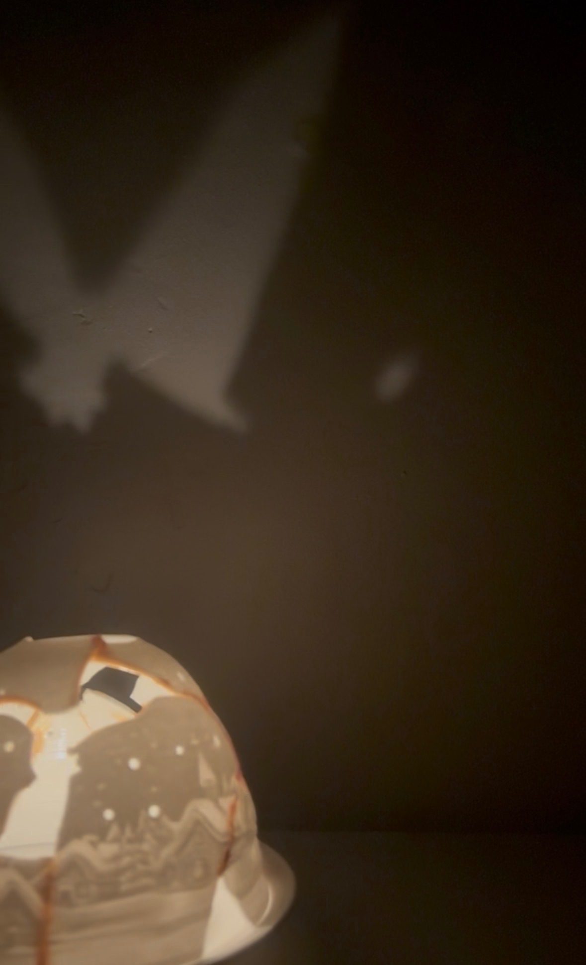 A mended tea light holder spinning and reflecting on the wall