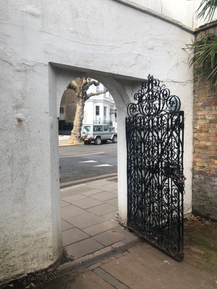 black gate with intense detail in Holland Park, the black metal gate is not closed nor fully open