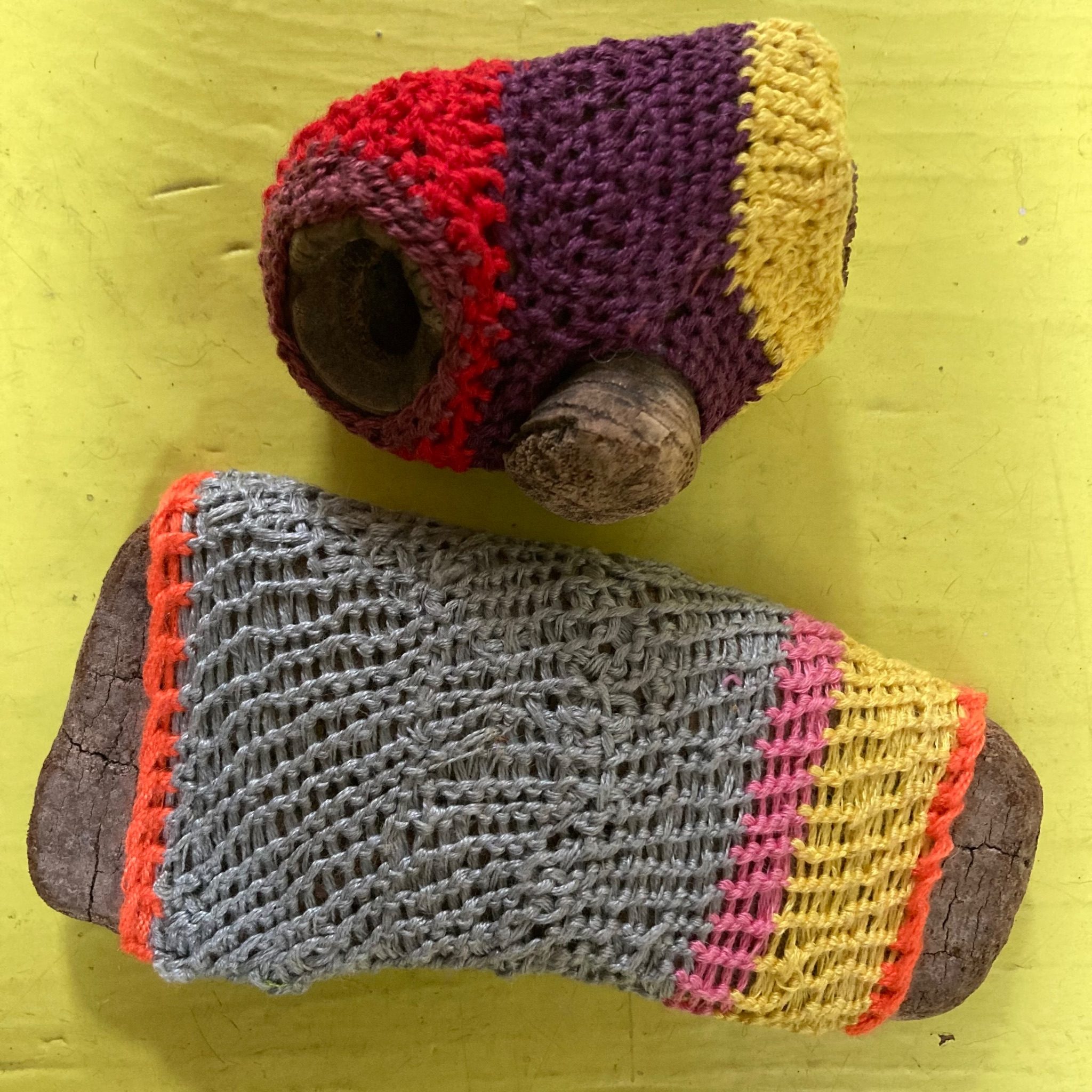 two small pieces of drift wood knotted over with coloured cotton thread, on yellow wooden floor