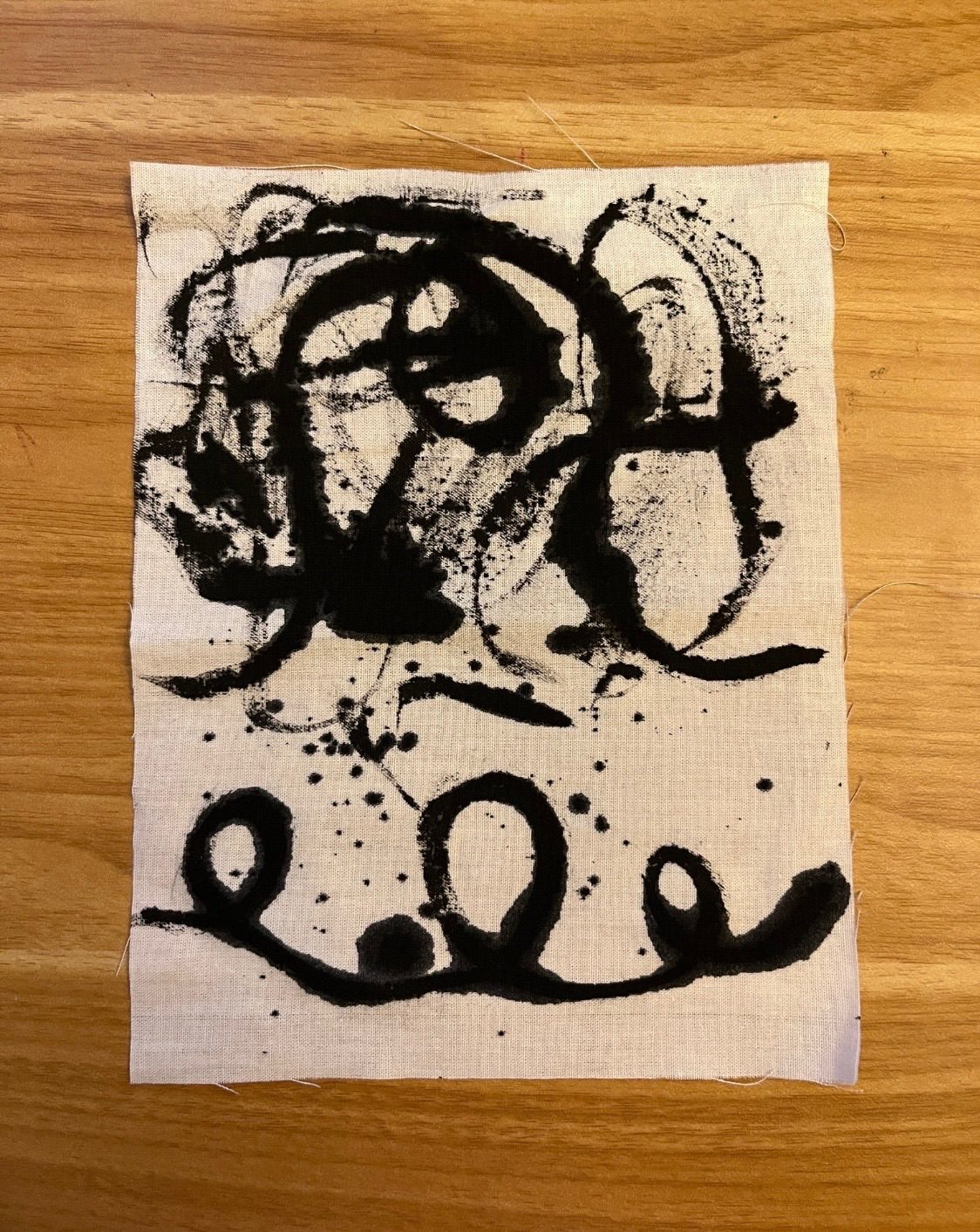 Inky black sketchy marks on a piece of white fabric