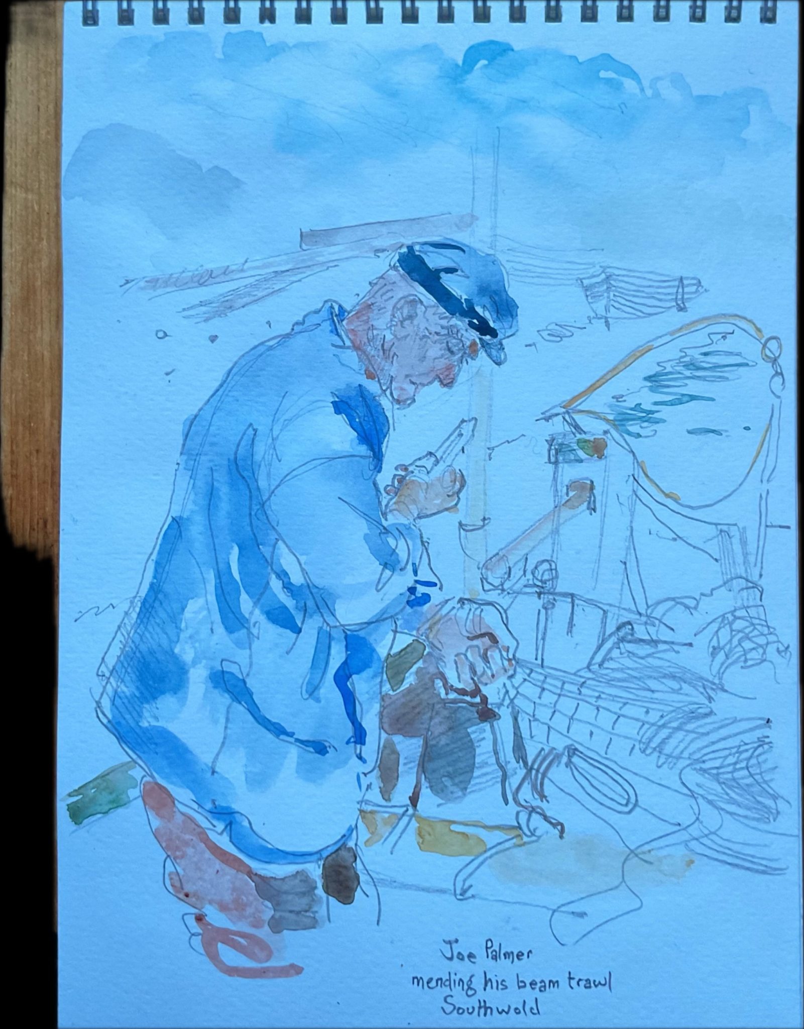 A weather beaten fisherman mends his nets aboard his boat moored at Southwold Suffolk UK