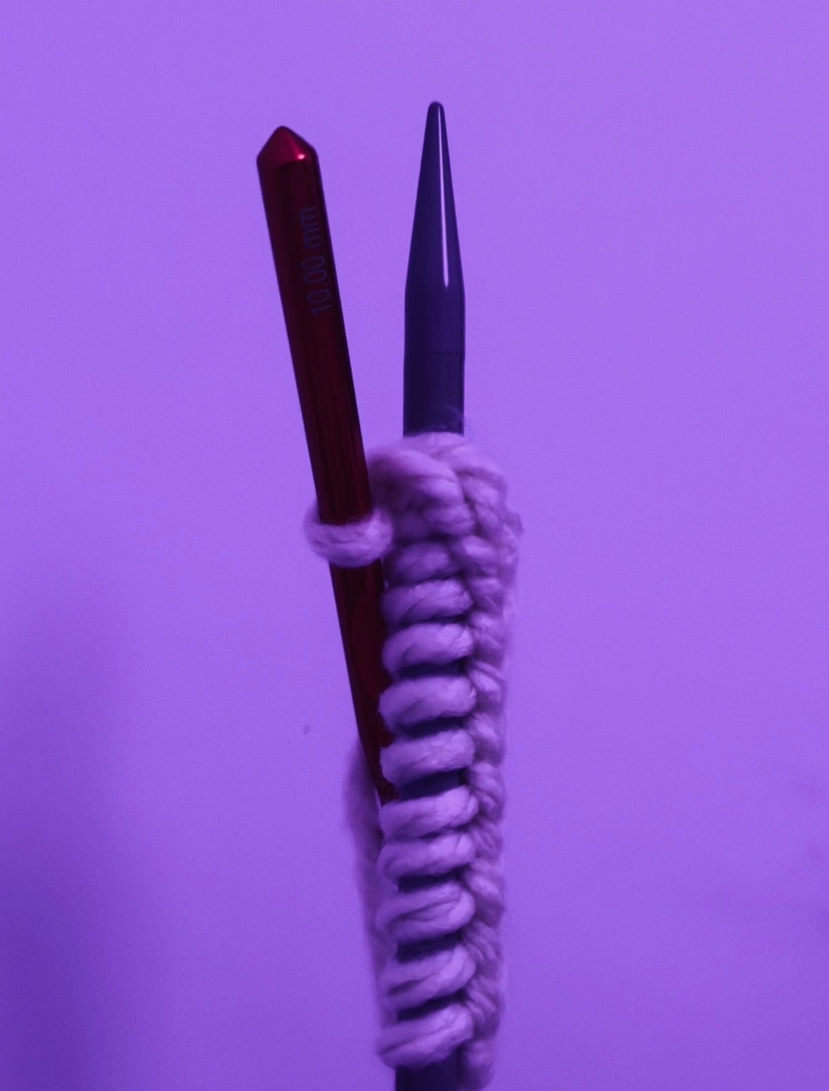 photo of a knitting needle with some casted on stitches, and a crochet hook twisted in the active yarn, almost looks like the knitting needle is wearing some yarn monstrosity & holding an oar but frankly it’s up to interpretation i’ve run out of ideas!
