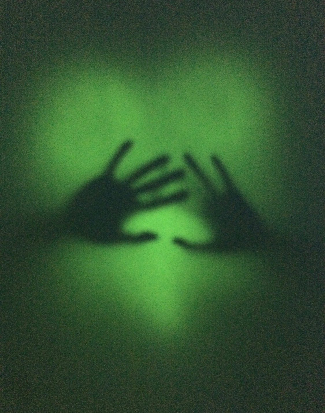 An over exposed after image of hands silhouetted by a heart shape