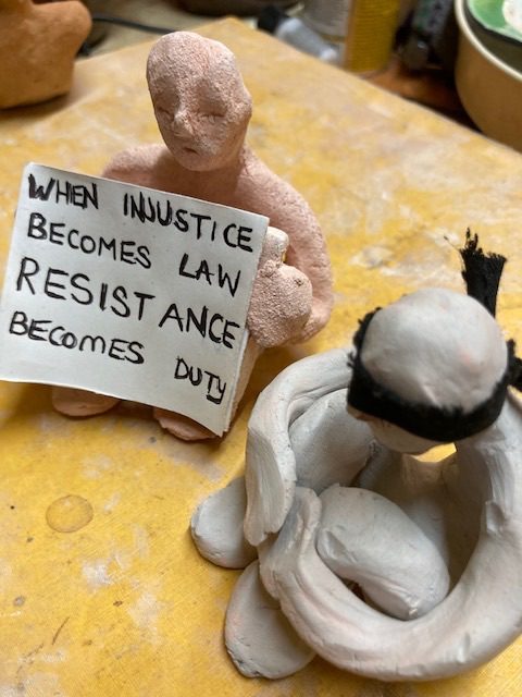Blindfolded clay person next to a placard holding one.