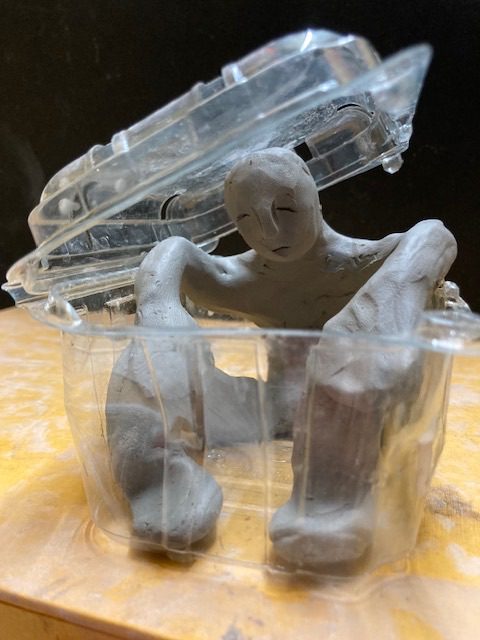 Clay person sitting in empty plastic packaging