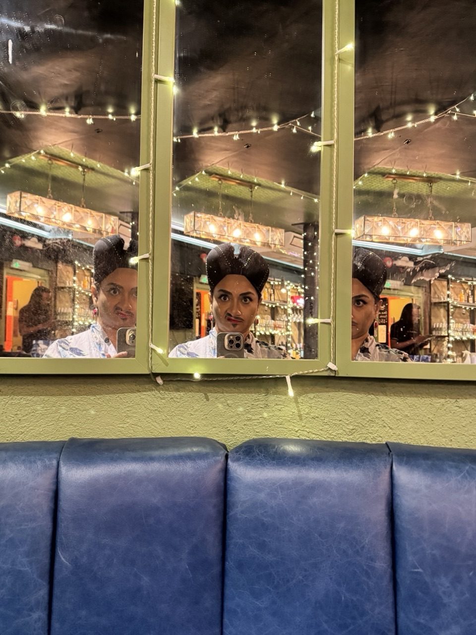 The photograph is taken at a cabaret club. It captures mirror reflection of the artist, a Drag-Thing, right before the house opens.