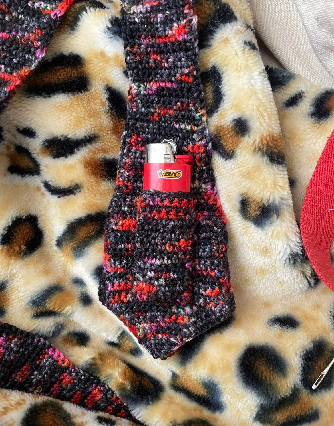 A crocheted neck tie, with a small pocket holding a lighter