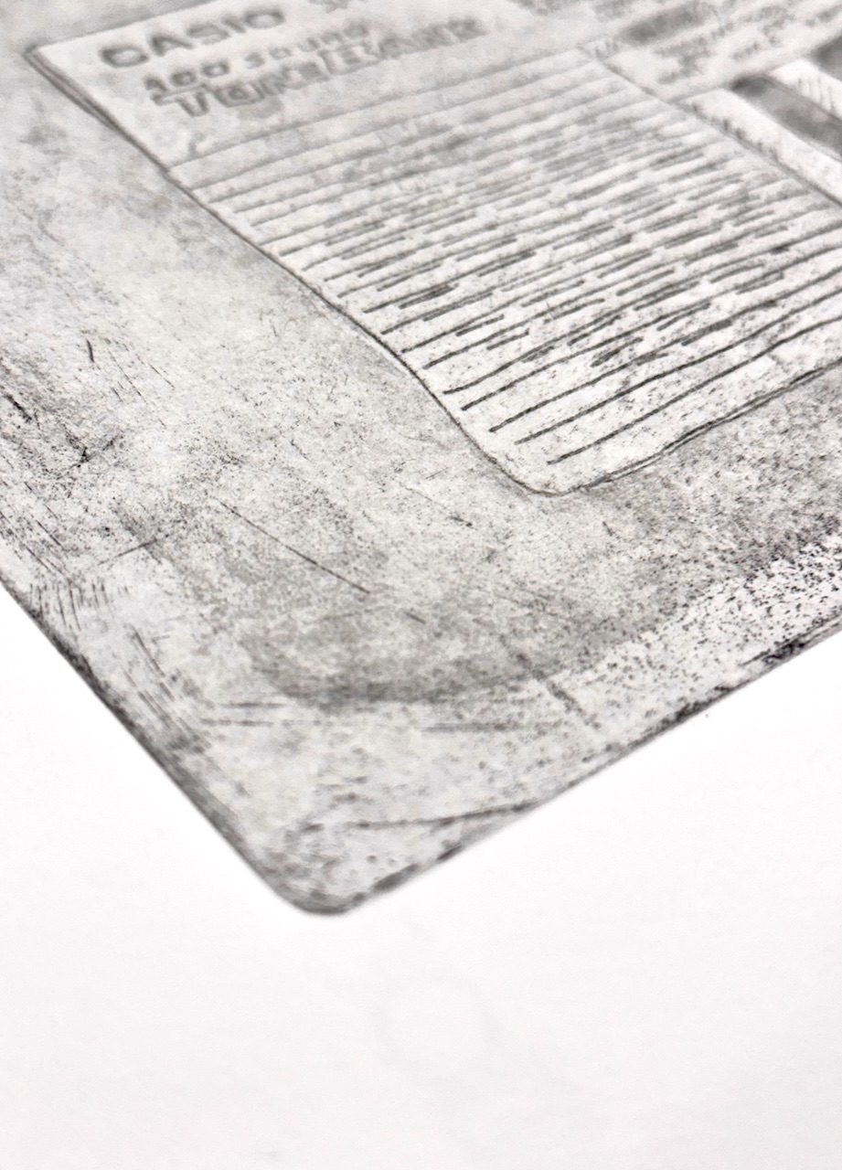 Photograph of the corner of an etching of a Casio keyboard