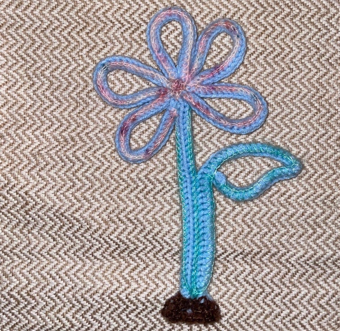 A crochet flower and leaf sprouting from a seed
