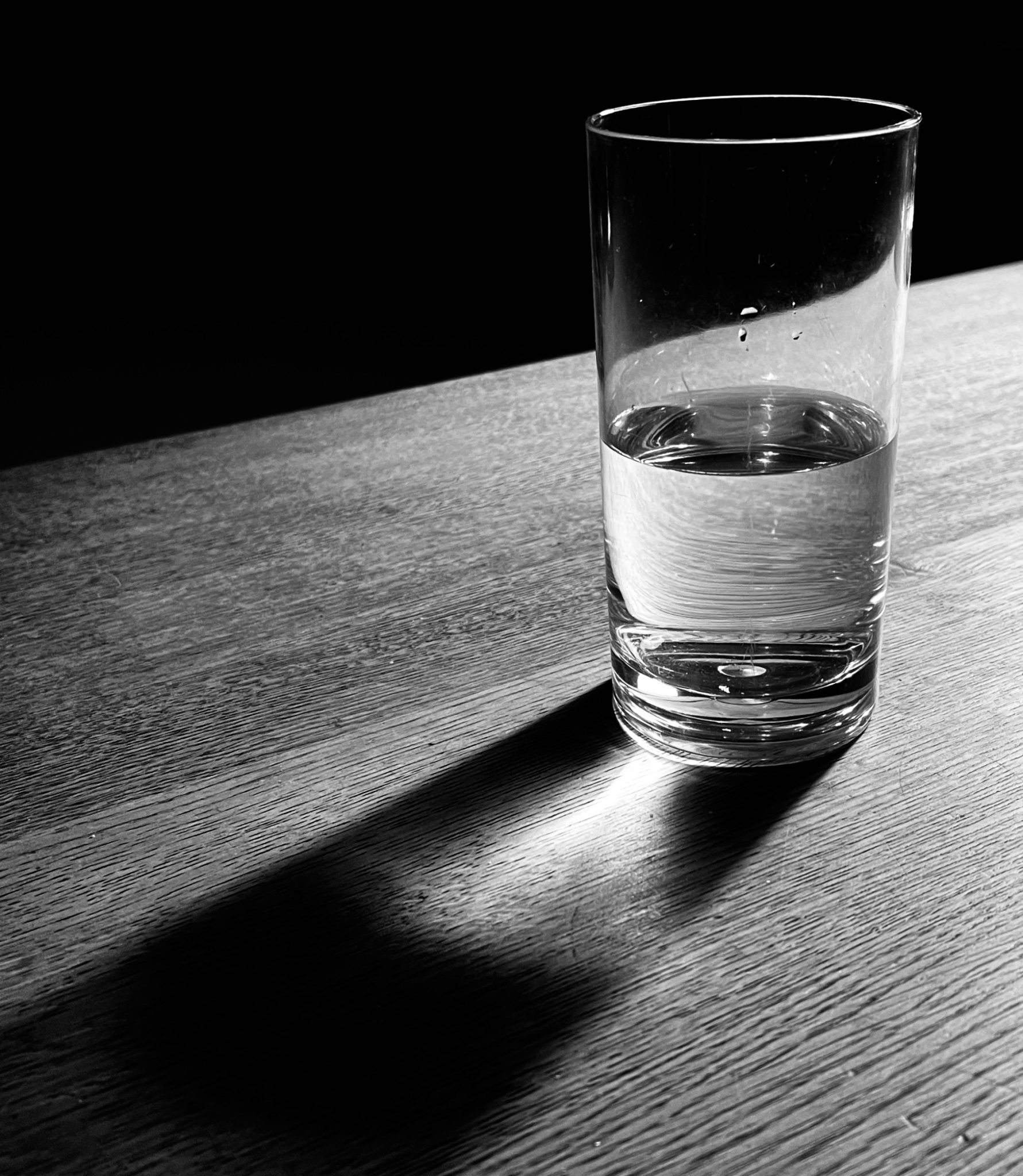 Black and white photograph of light falling through a glass casing a shadow with highlights