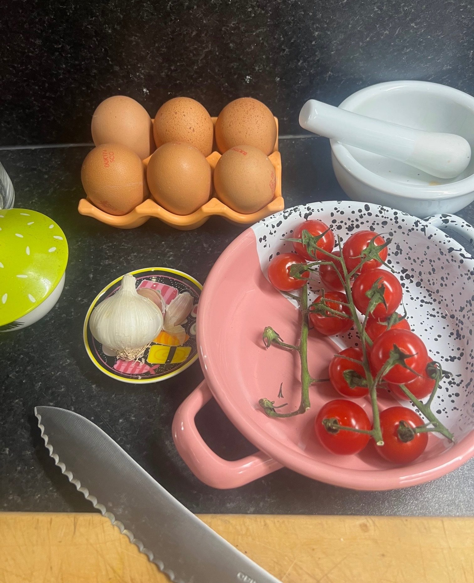 Photograph of kitchen worktop with eggs, tomatoes and garlic on colourful dishes