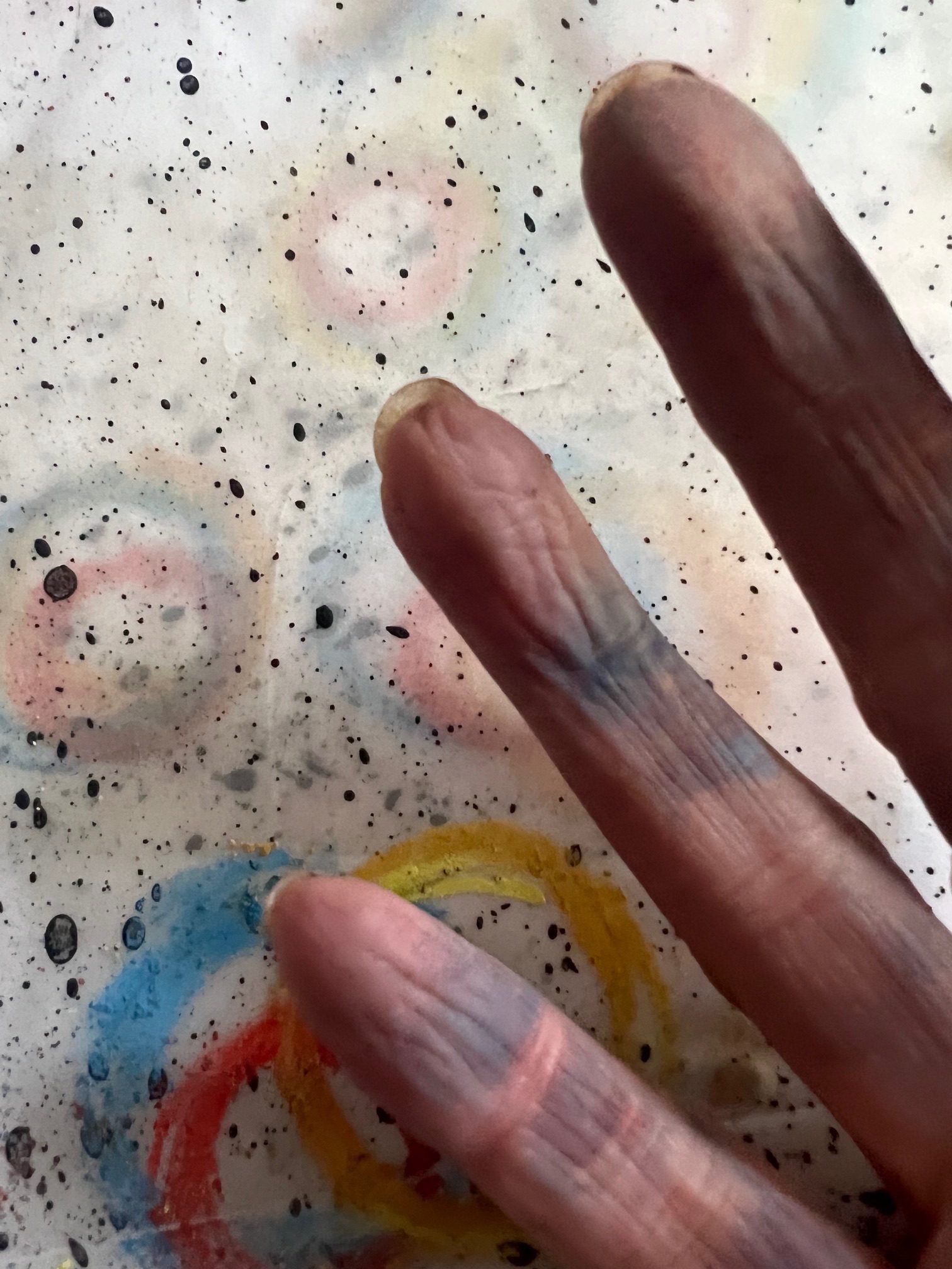 Photograph: Fingers of an upturned hand with smudged pastel above a piece of paper with some marks