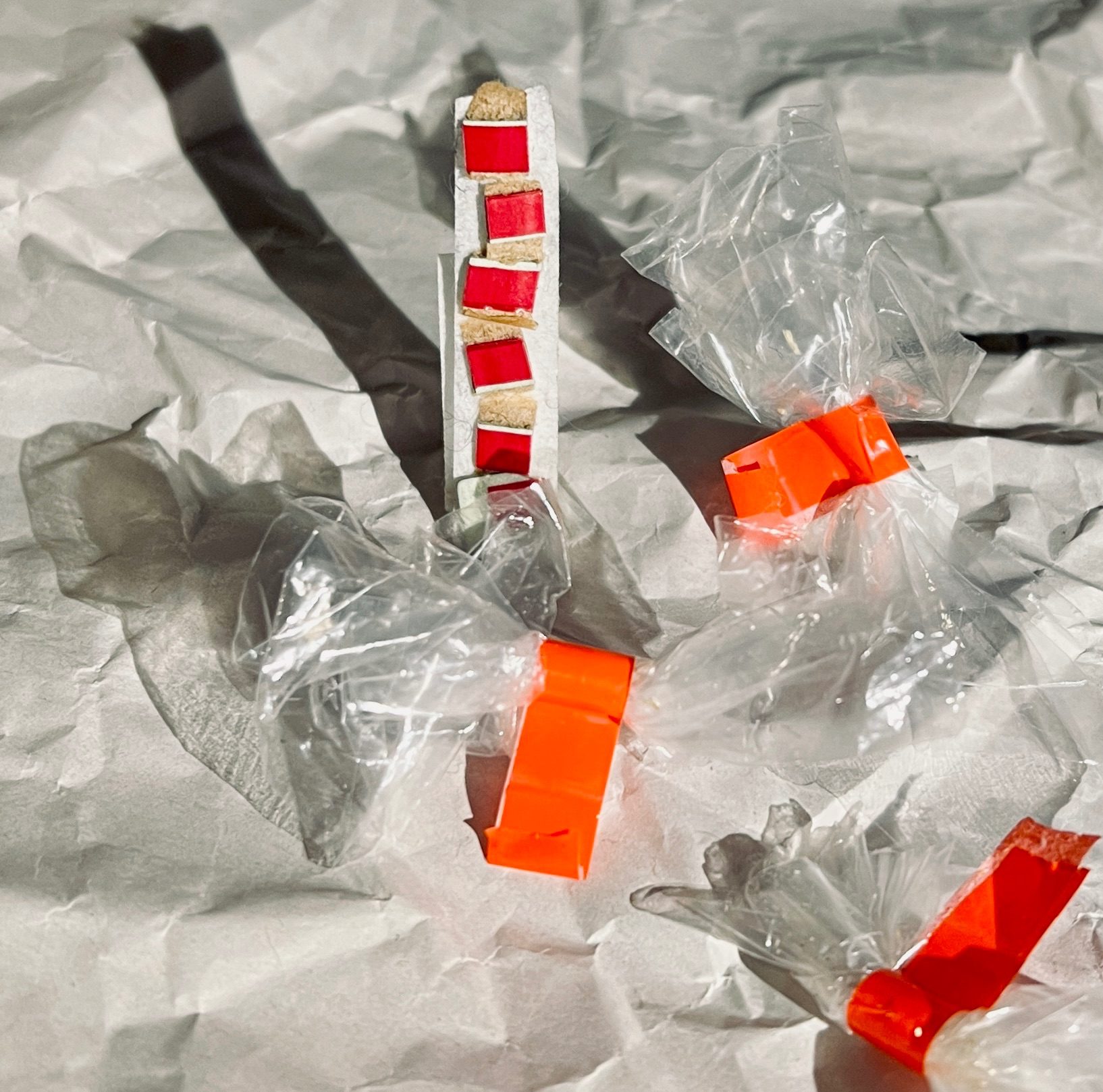 Abstract 3D composition made from packaging materials on top of crumpled newsprint paper - with a light casting dramatic shadows