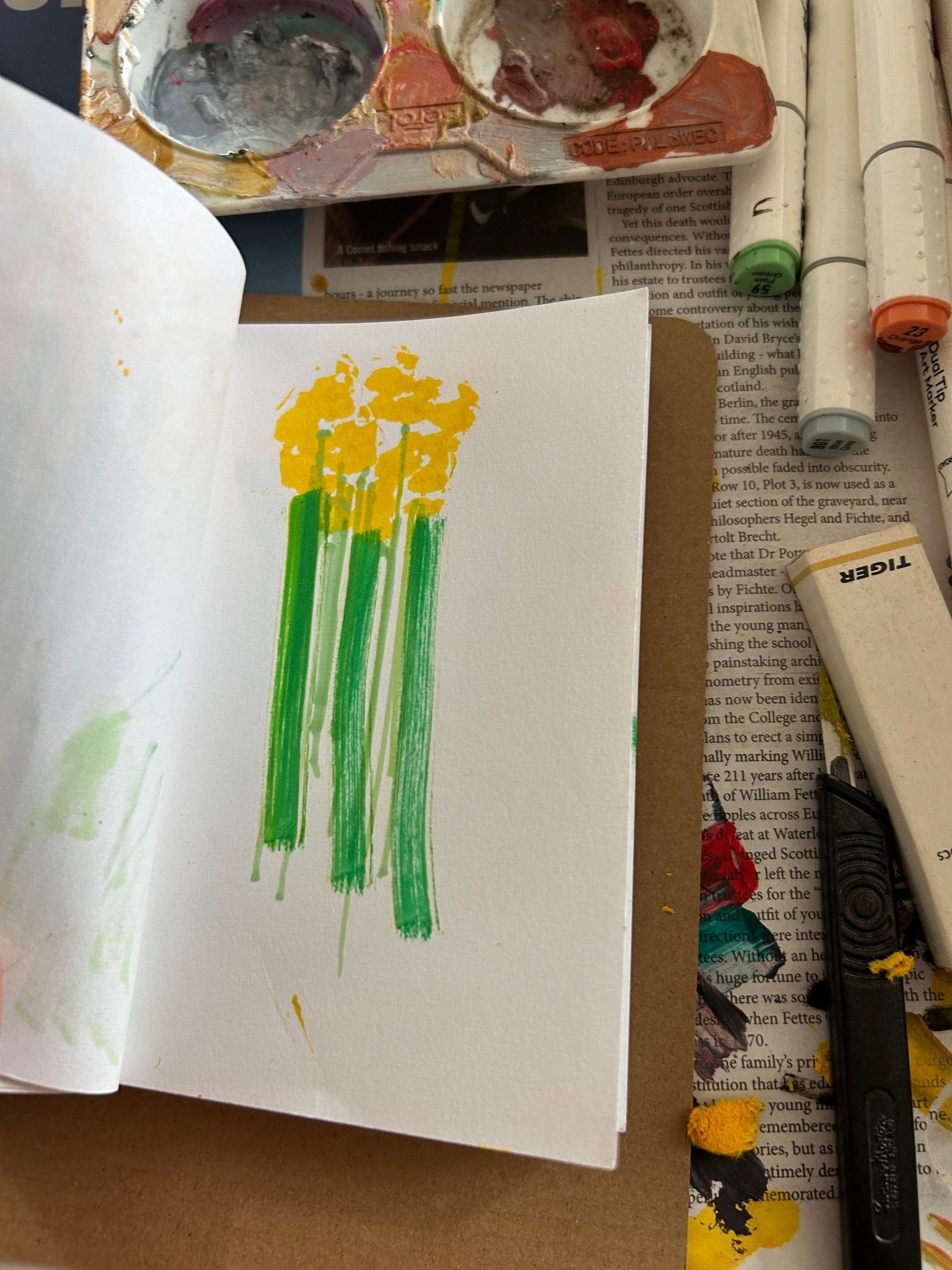 A photograph of a sketch book held open to show a number of green lines terminating at a yellow splash