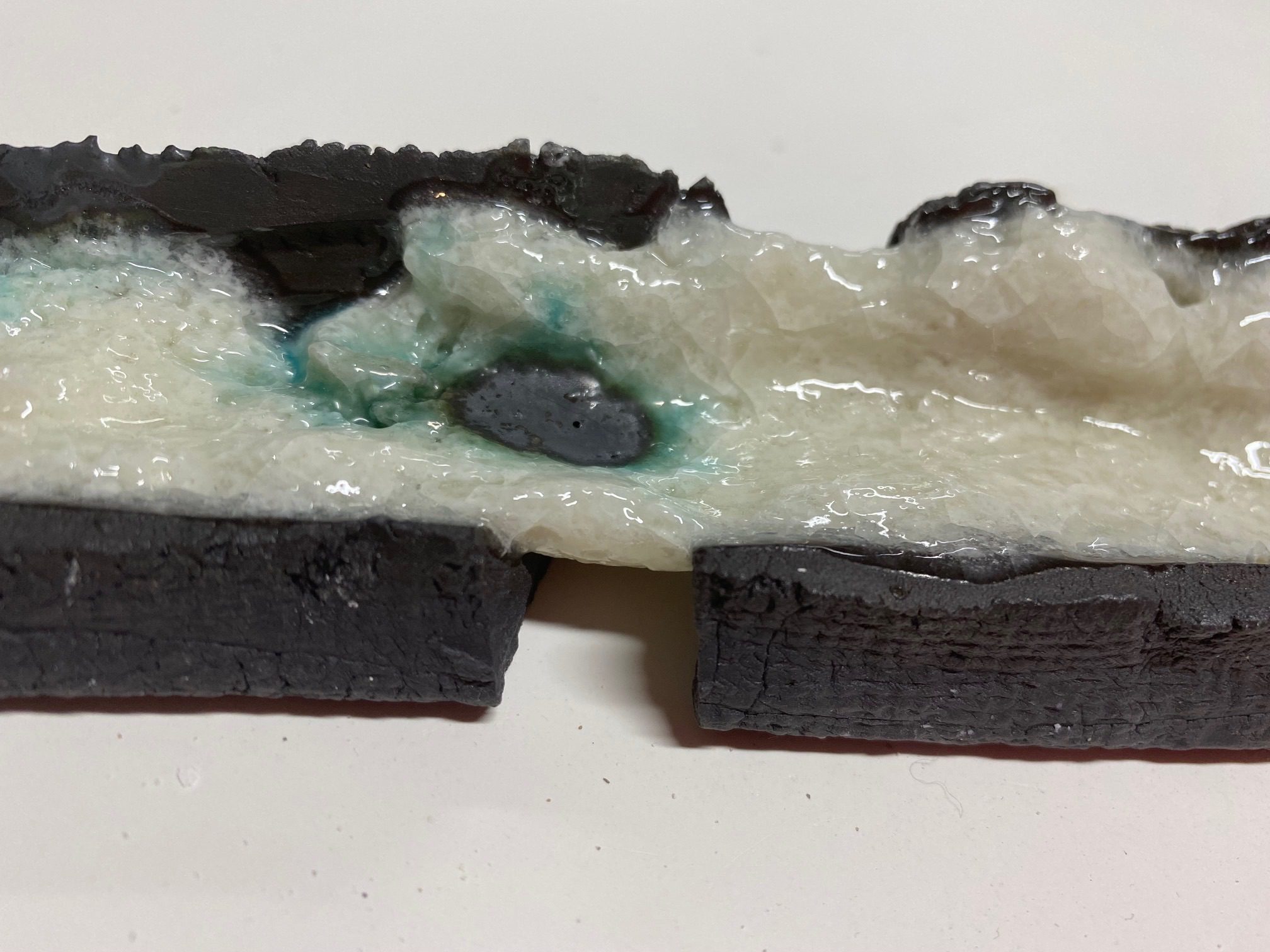 2 broken black clay pieces, and glaze joining it together
