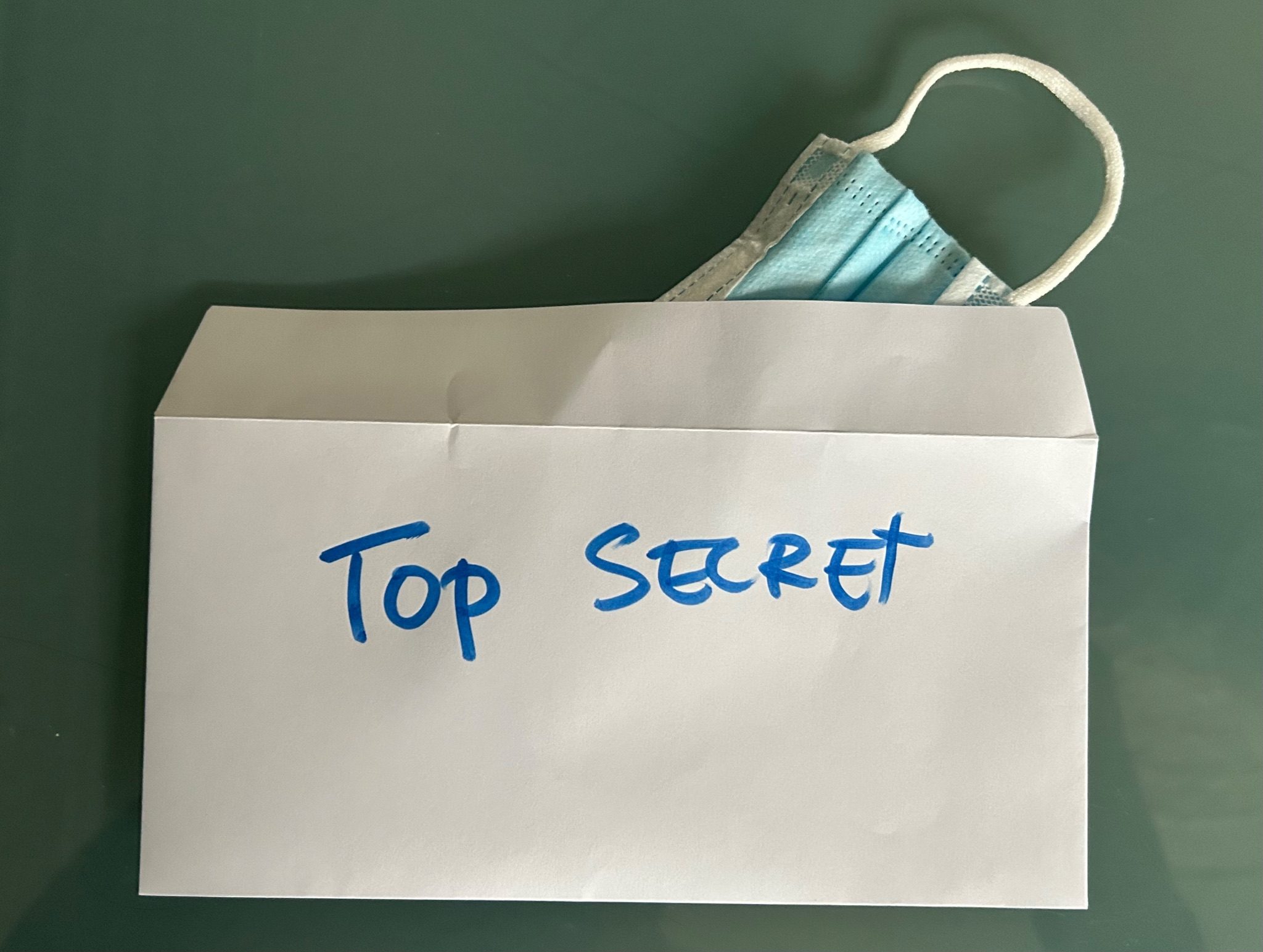 Envelope with top secret written on it and a germ mask peeking out the back of it