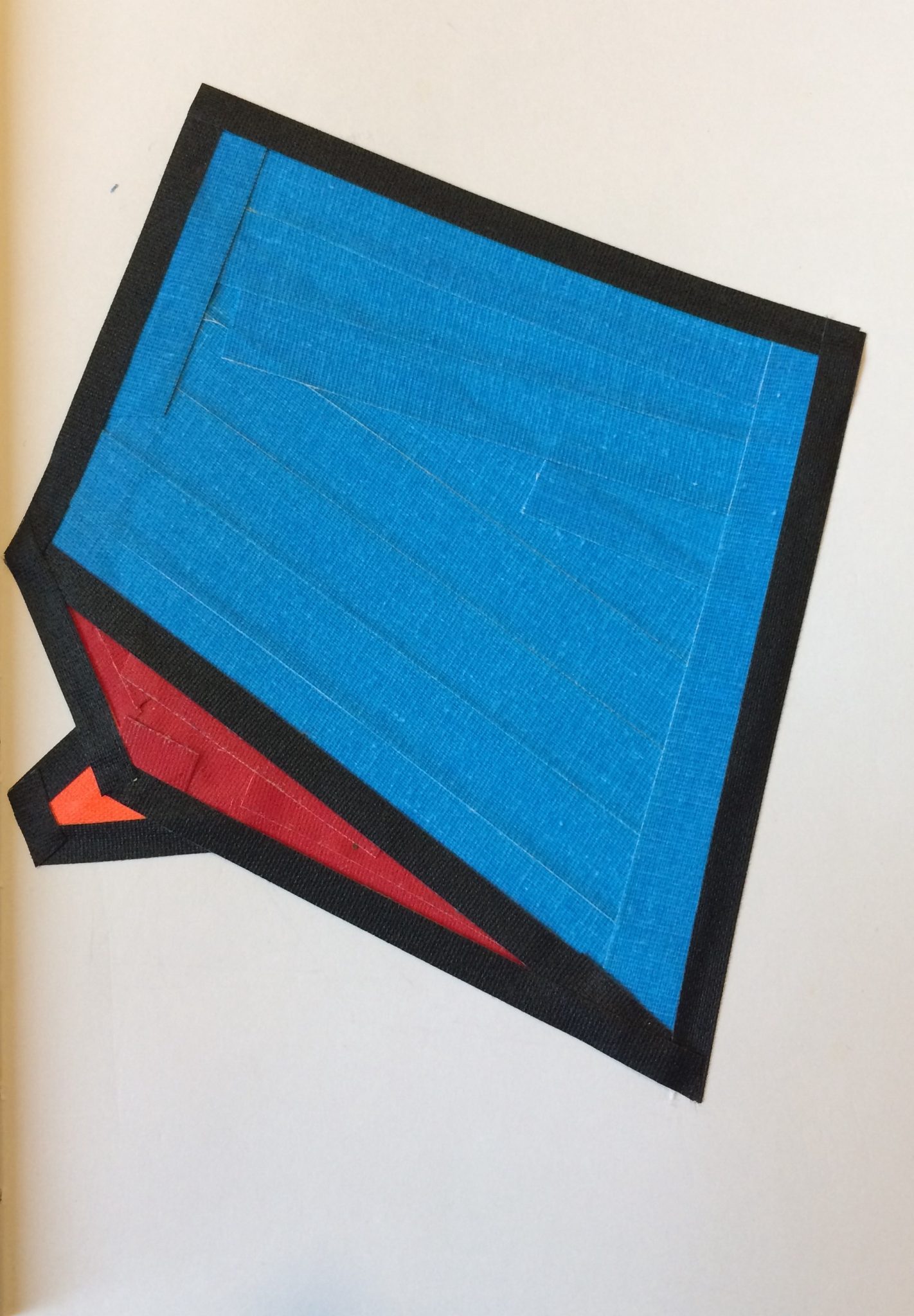 tape work, using an outline of black tape, and three colour shapes, blue 4 side polygon on top, red triangle below ,small orange 5 side polygon slightly covered up by red triangle. resembles a megaphone