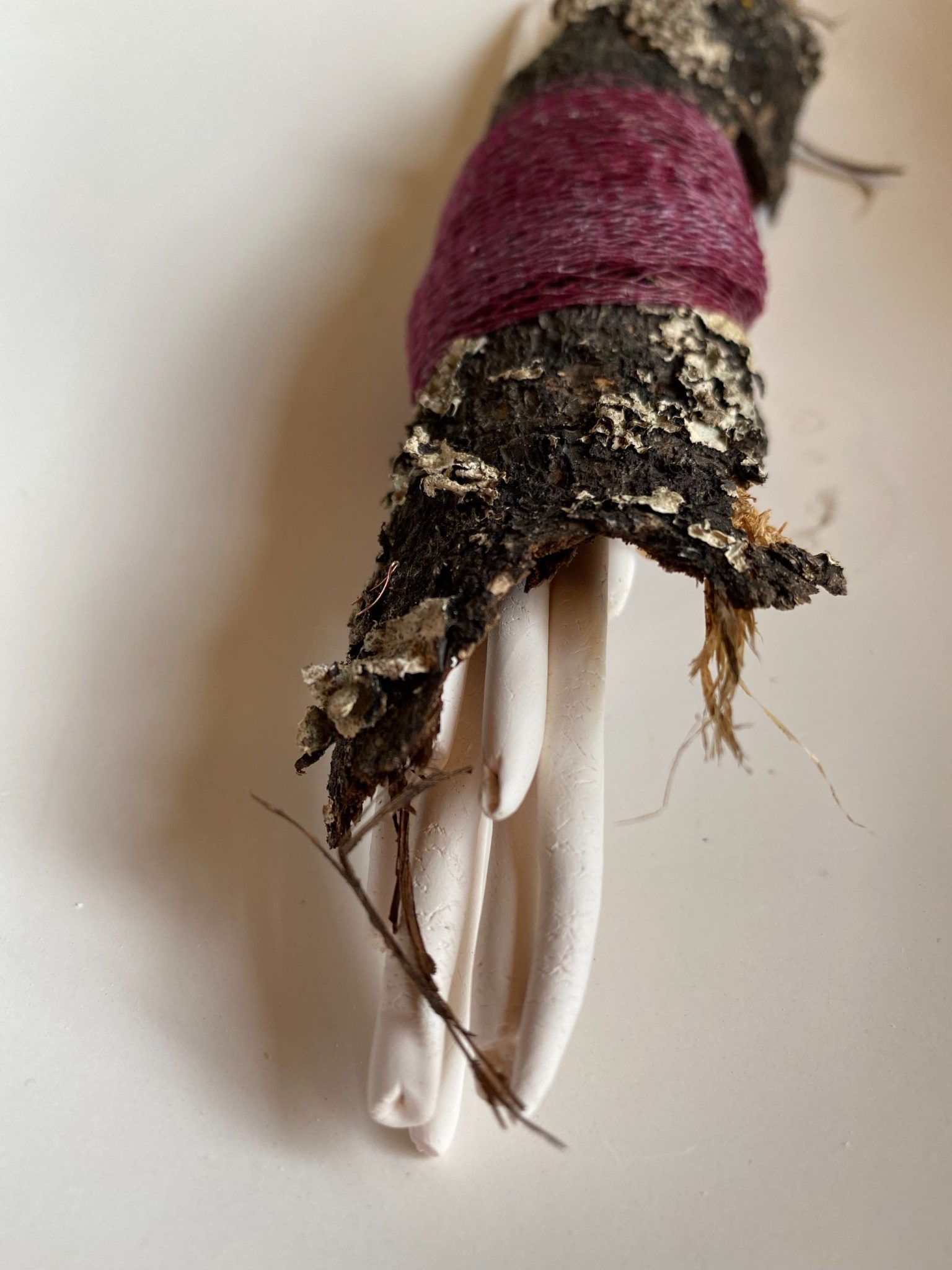 long porcelain coils wrapped in tree bark and red netting
