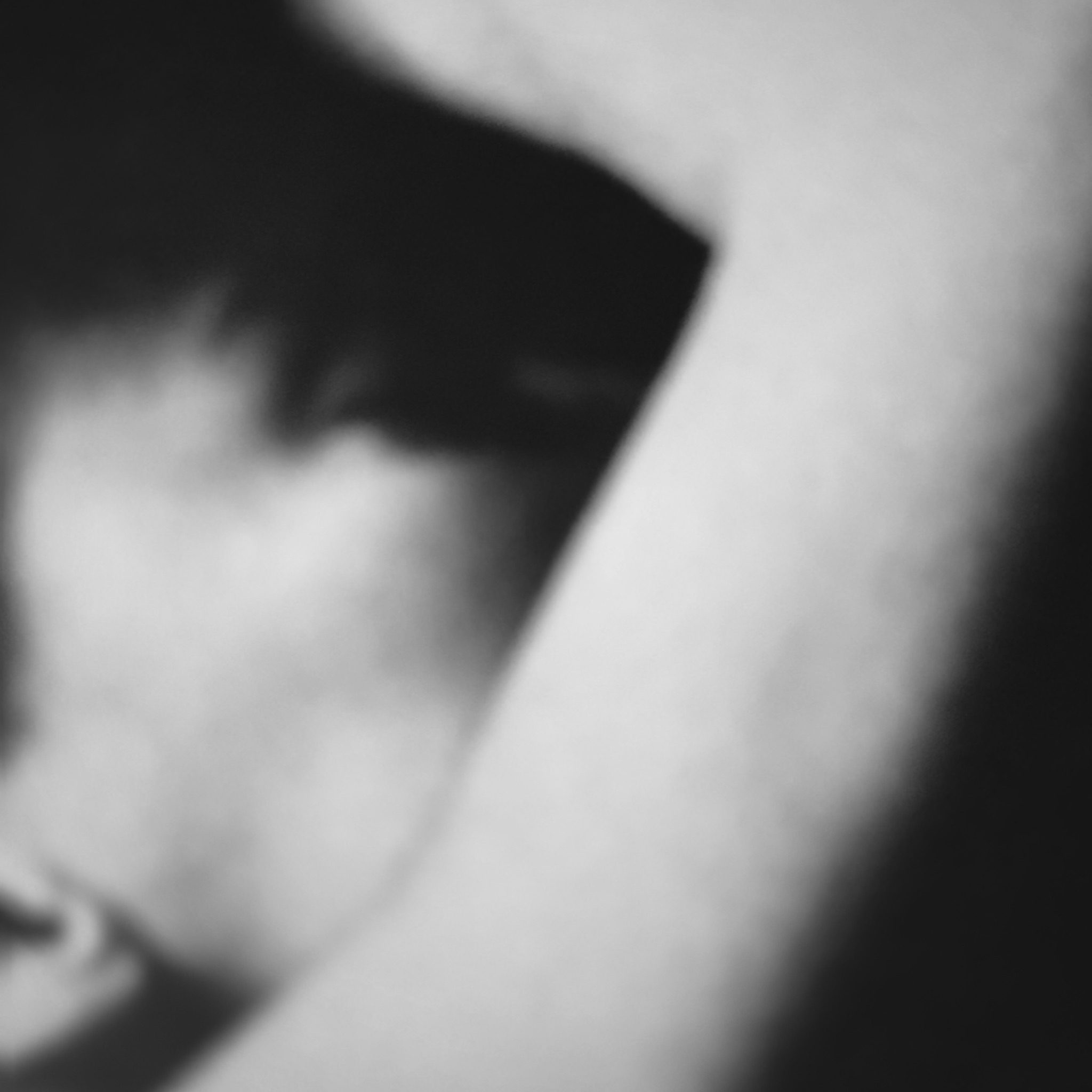 An abstract black and white photo of a woman’s arm holding her head.