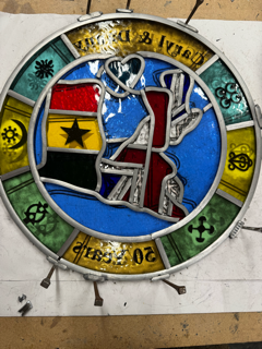 A rear/backwards view of leaded glass held together with pins, prior to soldering. Features flags of Ghana and UK.