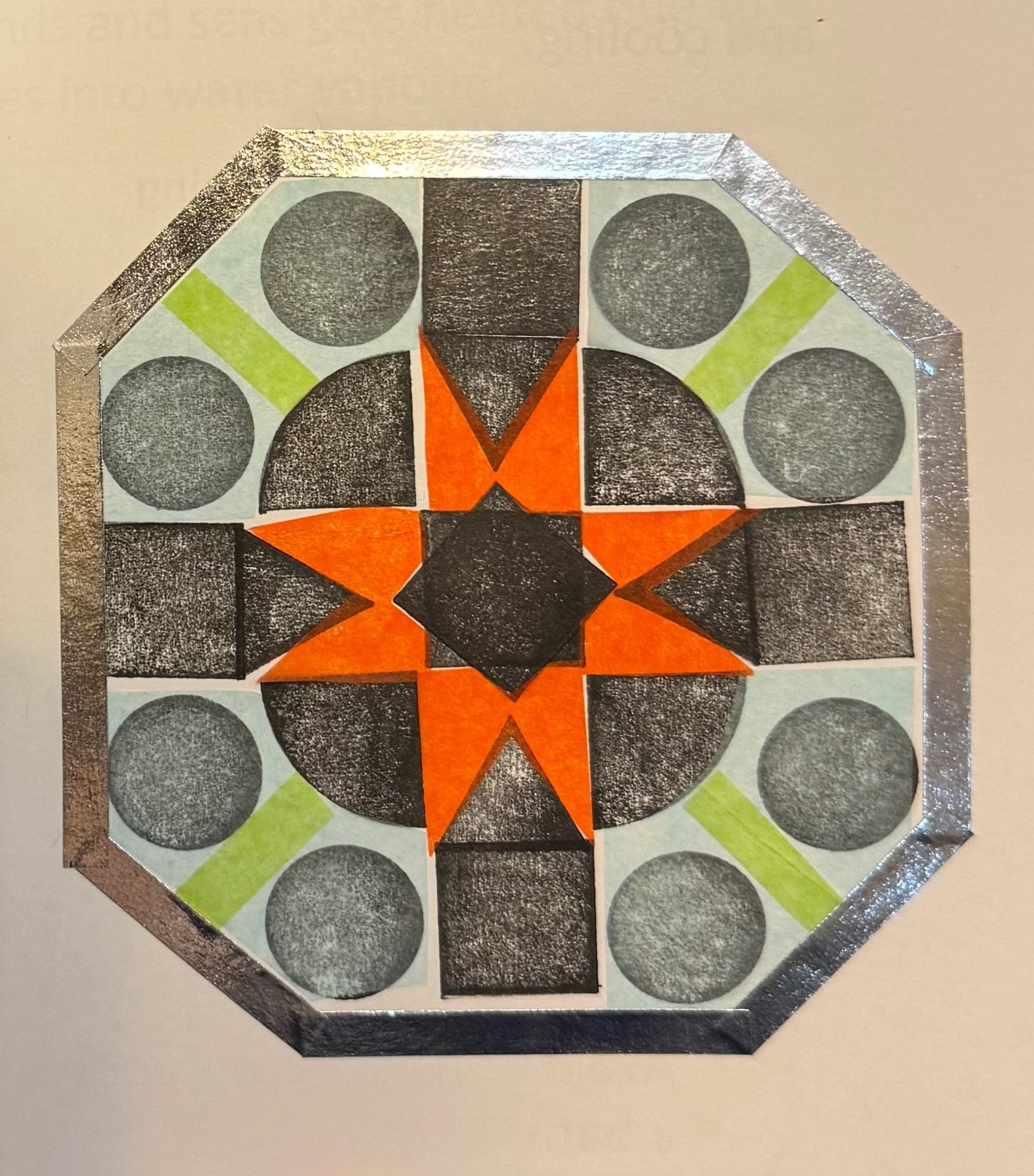 Black and white pattern made from triangles and squares, with coloured pieces of tissue paper and a silver tape border.