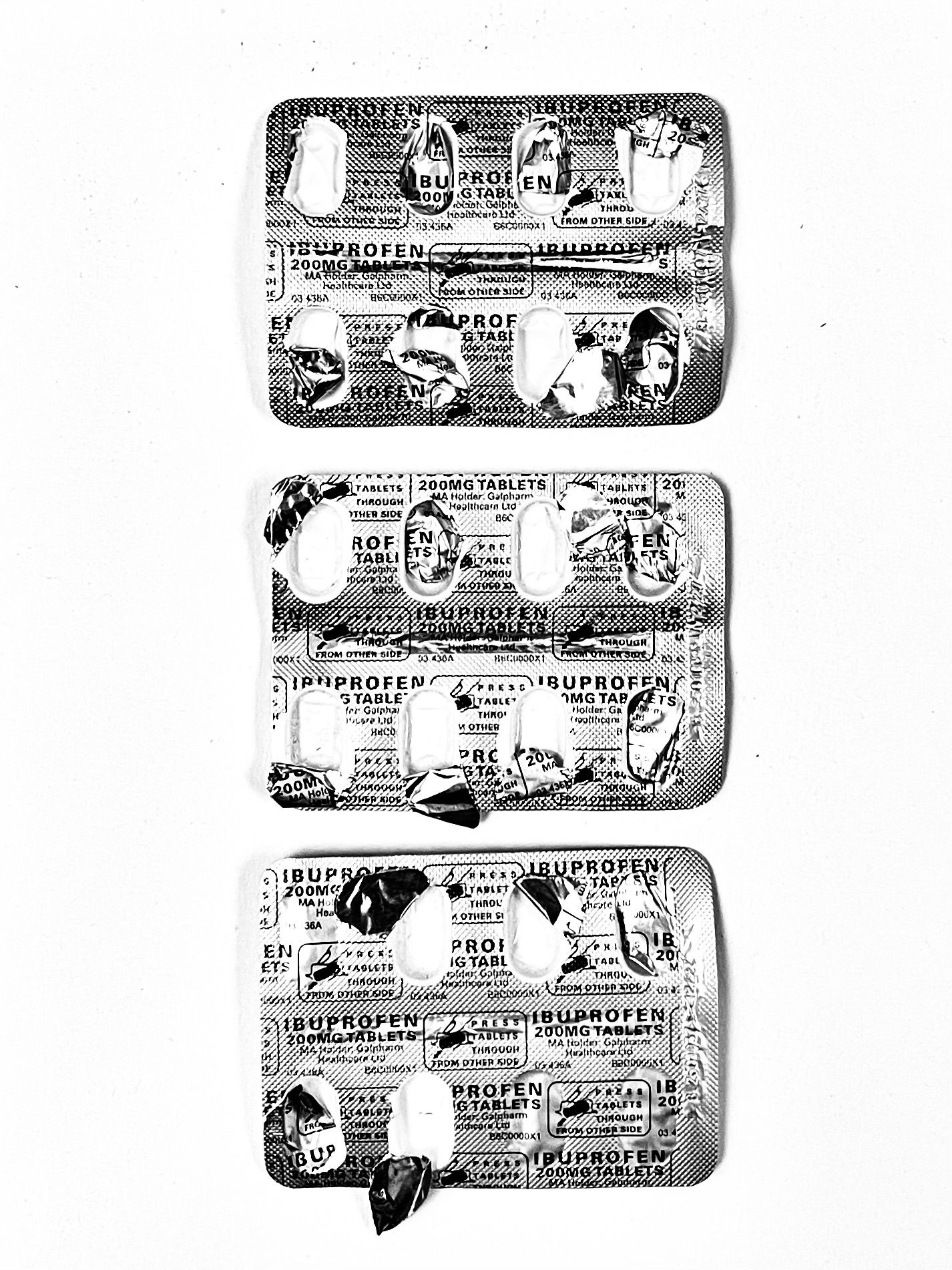 Black and white photo of 3 mostly empty blister packs of ibuprofen
