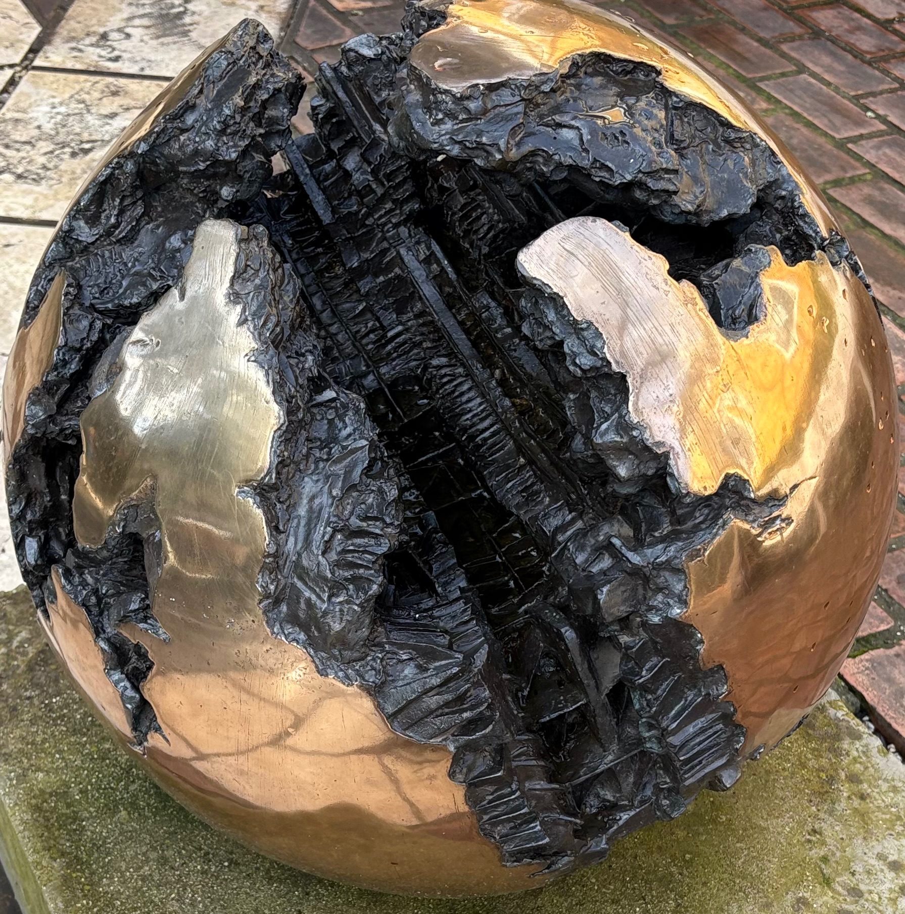 Photo of a spherical gold painted ball, riven apart to show a black jagged interior