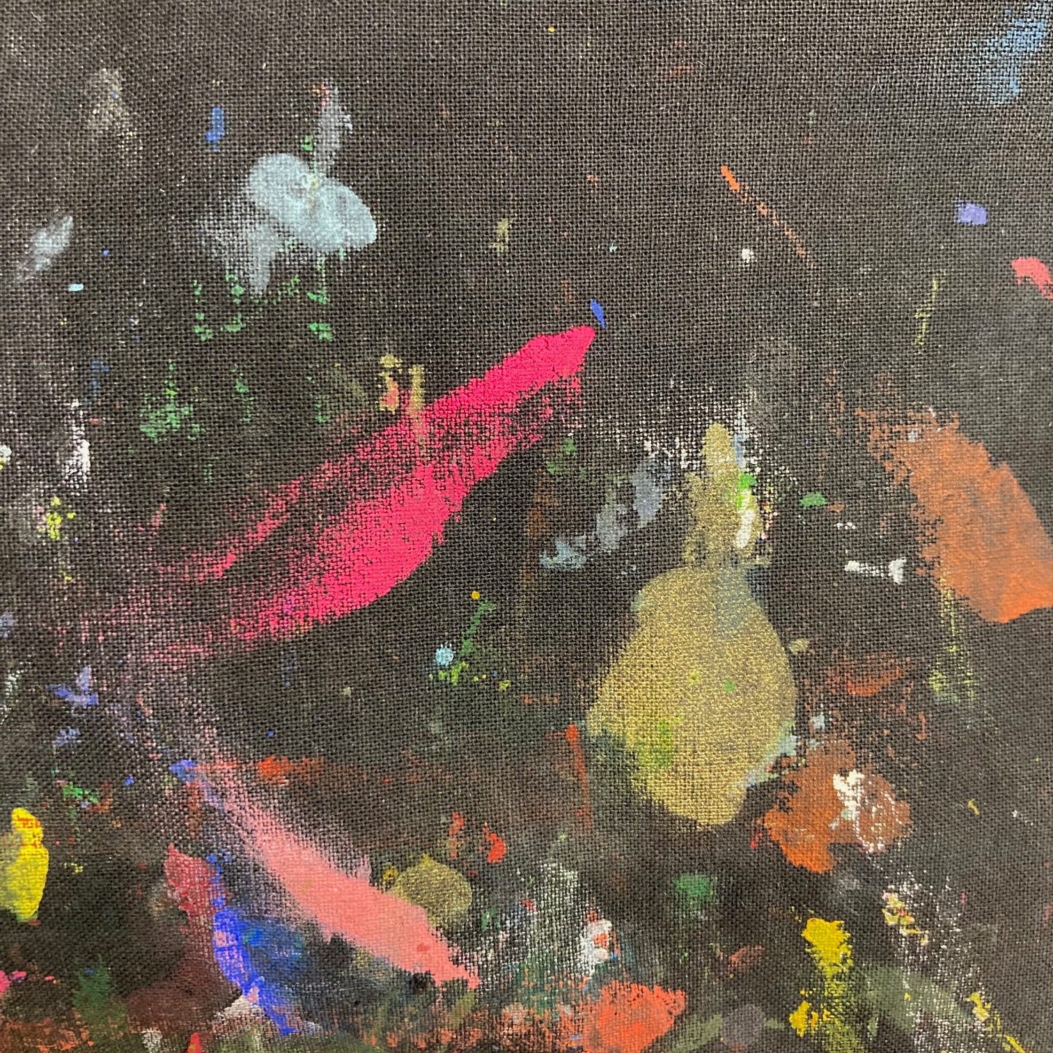 Close up of an ink covered smock - black fabric covered in smears of brightly coloured printing ink