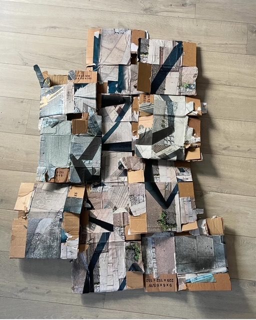 A mess of boxes on the floor with some photos of parts of black lampposts on