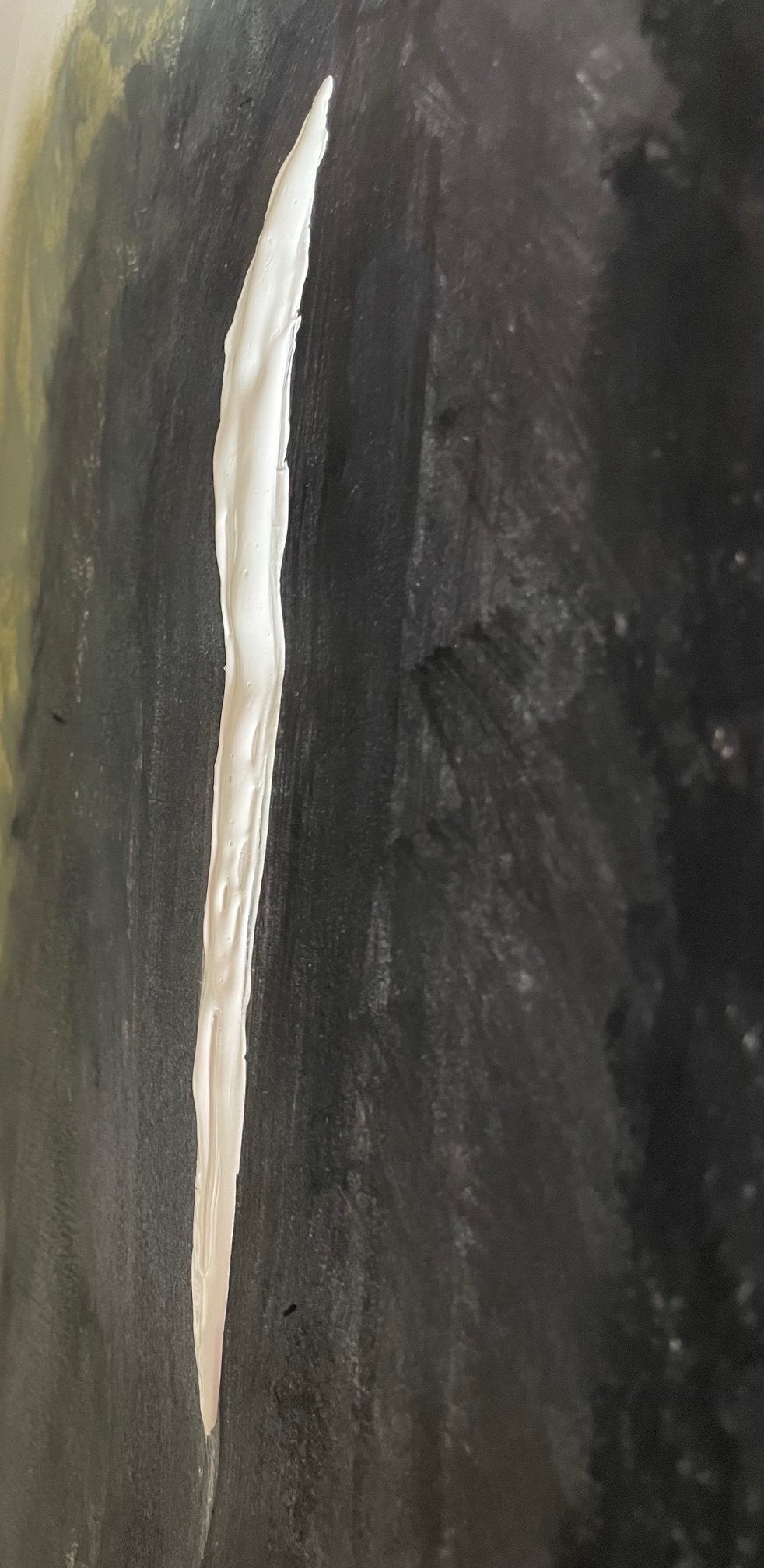 A white painted vertical slit against a painted black background