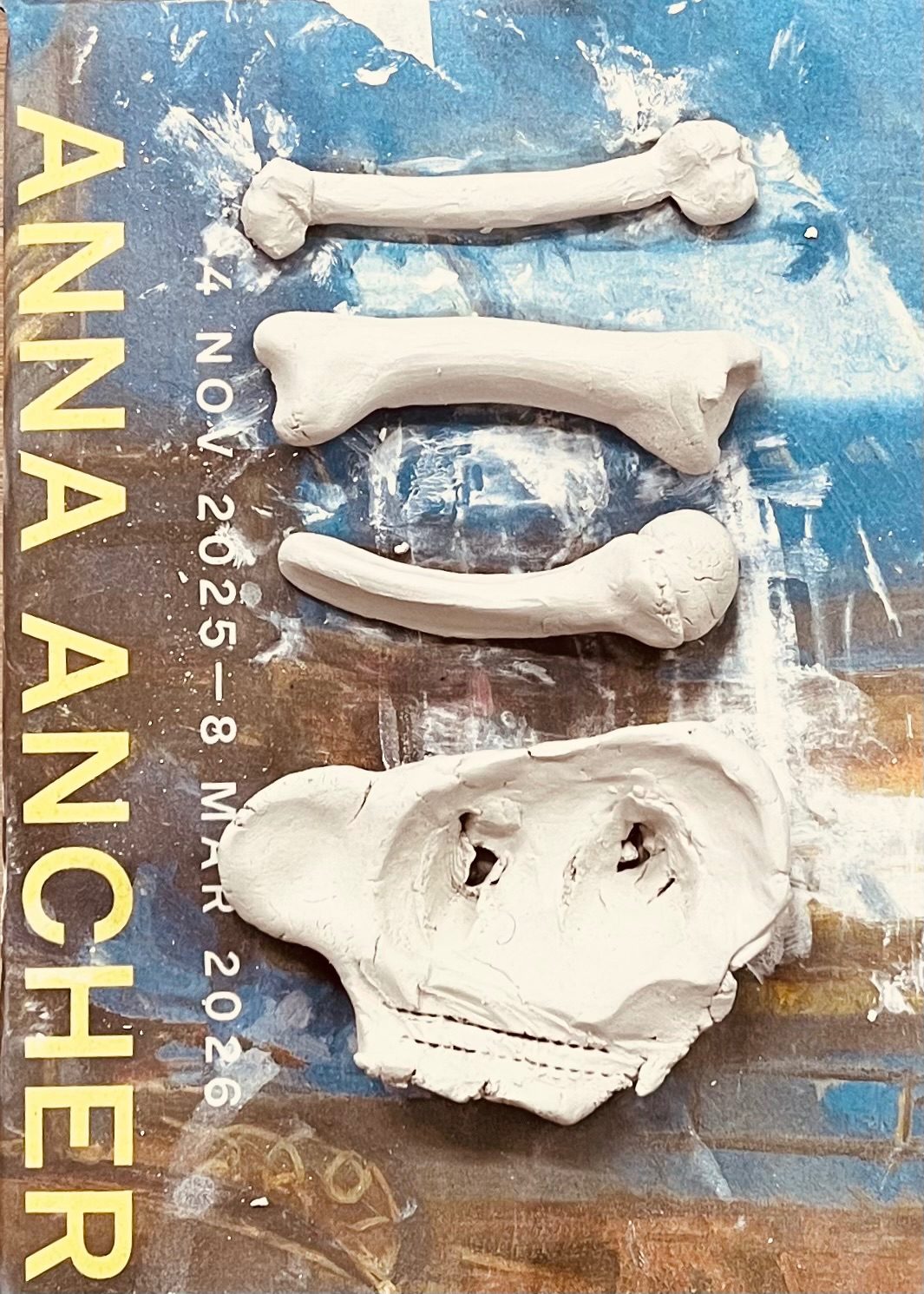 Bones made of clay rest on a sheet of newsprint with an advertisement displaying the words Anna archer.