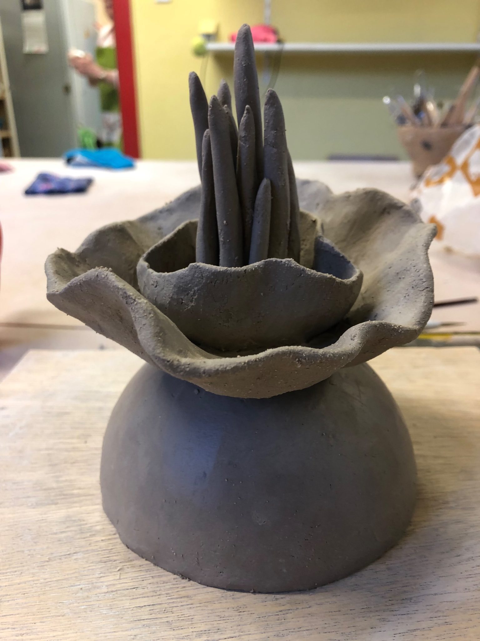 Work in gray clay, 2 superimposed half spheres on the contrary. In the upper sphere a rounding and tips, like a corolla and a pistil sa