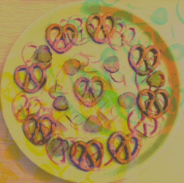 psychedelic digital edit of cheese, pretzels and gherkins displayed decoratively on a plate