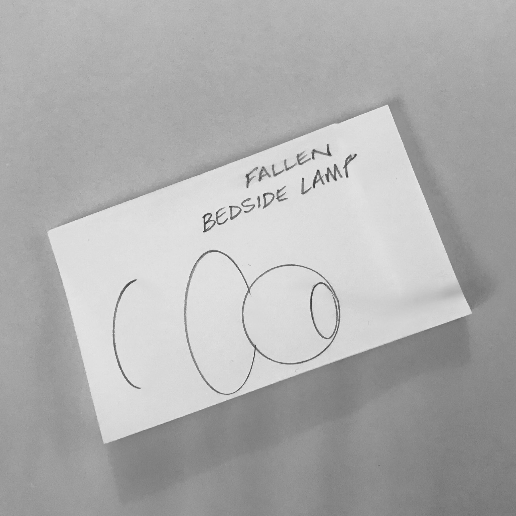 A pencil drawing of the partial outline of a bedside lamp on its side.