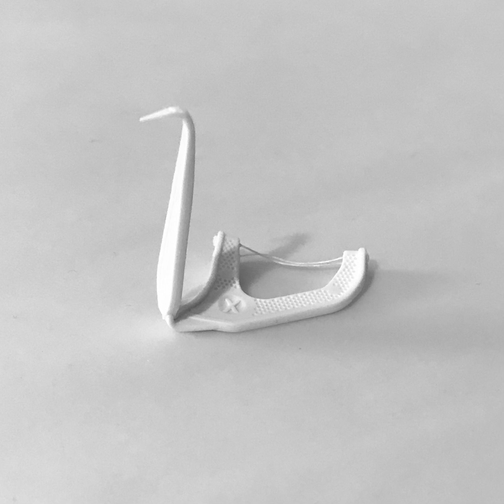 A dental floss pick bent into a shape vaguely resembling a swan