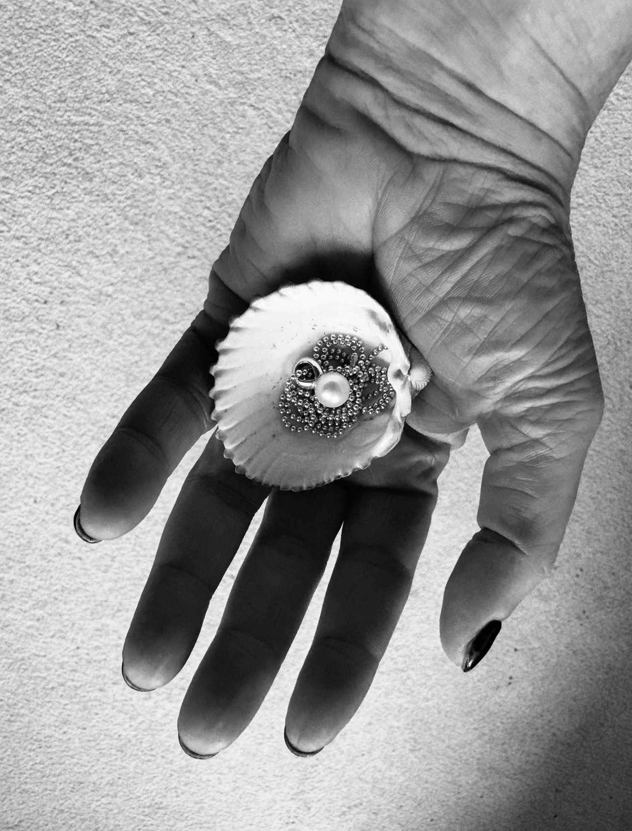 A photograph my palm with a found shell, nesting a pearl necklace. A simple artistic shift of perspective.