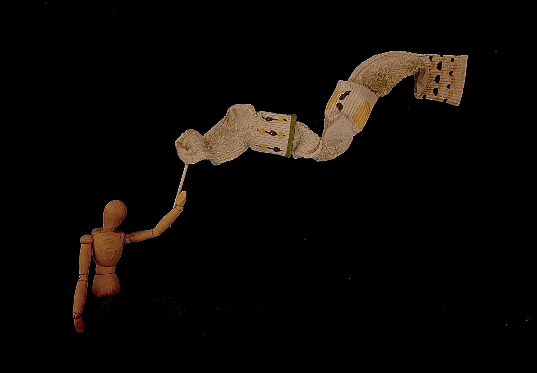 Photograph of a mini drawing mannequin holding a flag made out of socks