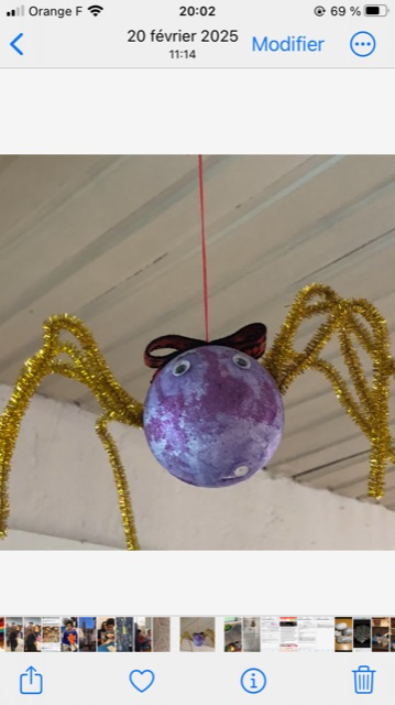 A spider made with a polystyrene ball, with golden pipe wax legs, the body is painted purple and the eyes in glass