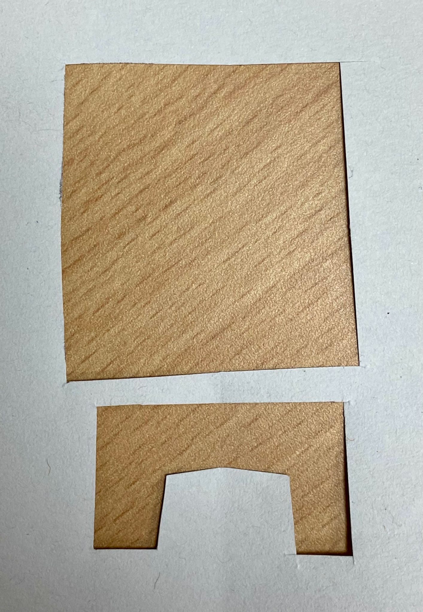 Cut out drawing of a dwelling shape with the wood of the table underneath