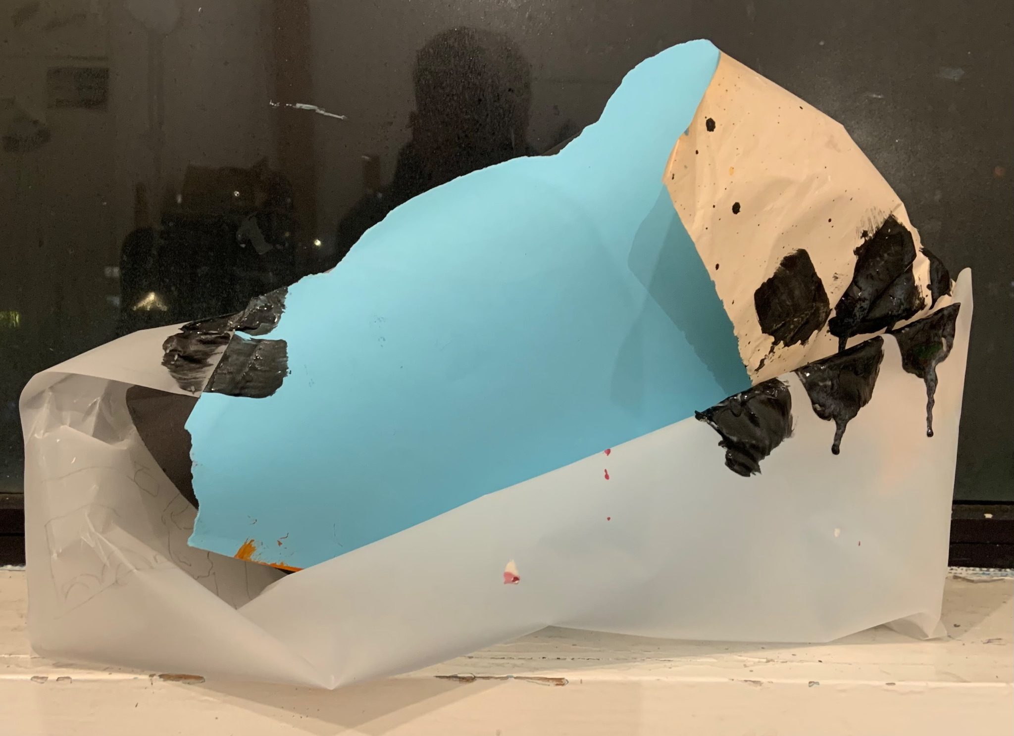 sculpture on a windowsill made from tracing paper blue card and with some paint marks