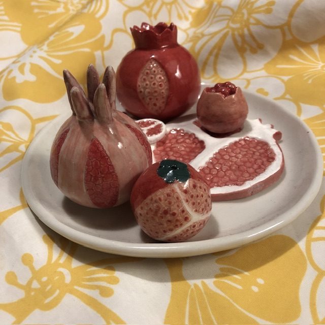 A fruit plate in red and pink enameled porcelain., whole or sliced fruit.