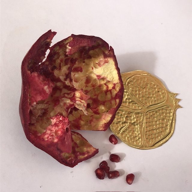 Half a fruit pomegranate is emptied of its seeds. Some seeds are scattered next to it, with a round slice of pomegranate. This one is made of pushed aluminum and gilded.