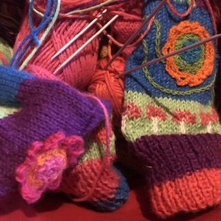 In a basket, balls in bright colors and wool gloves almost finished, in jacquart with patterns