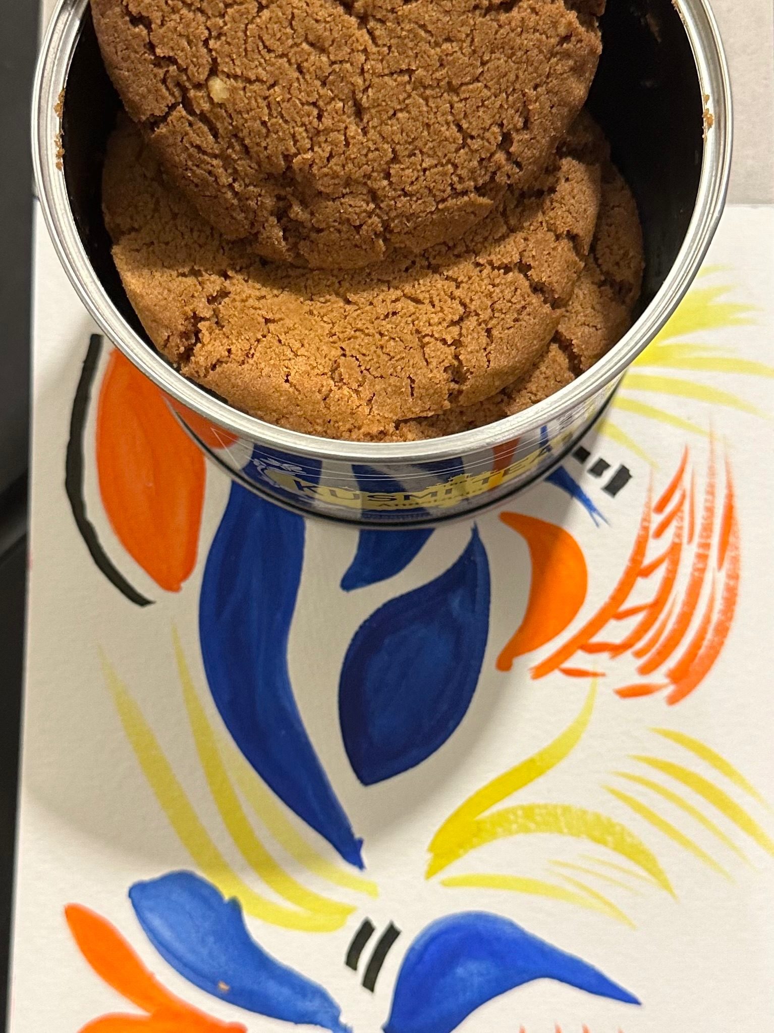 A photo of a tin of cookies over a watercolour sketch