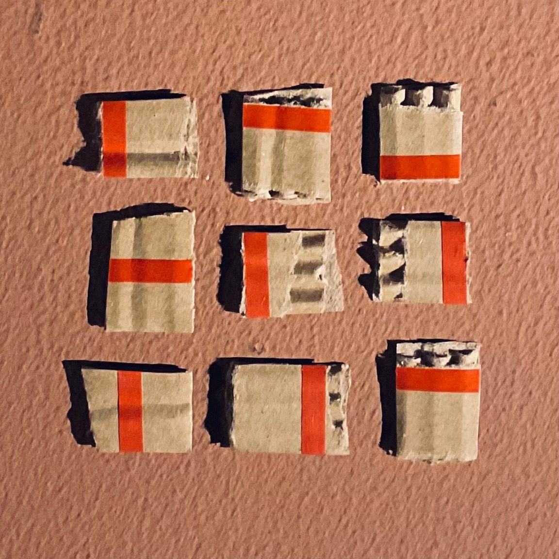 Grid of rough squares of bits of rip-strip from cardboard envelopes.