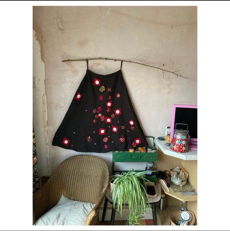 A dark brown wool skirt embellished with red circles of fabric.